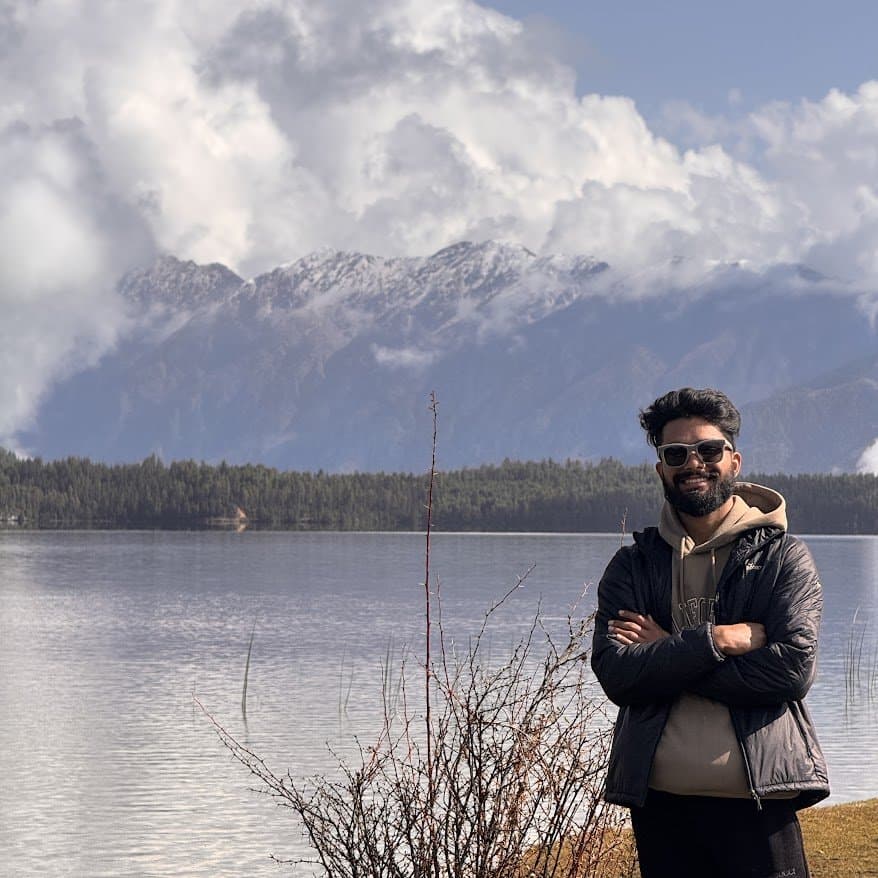 Standing by Rara Lake with snow peaks behind